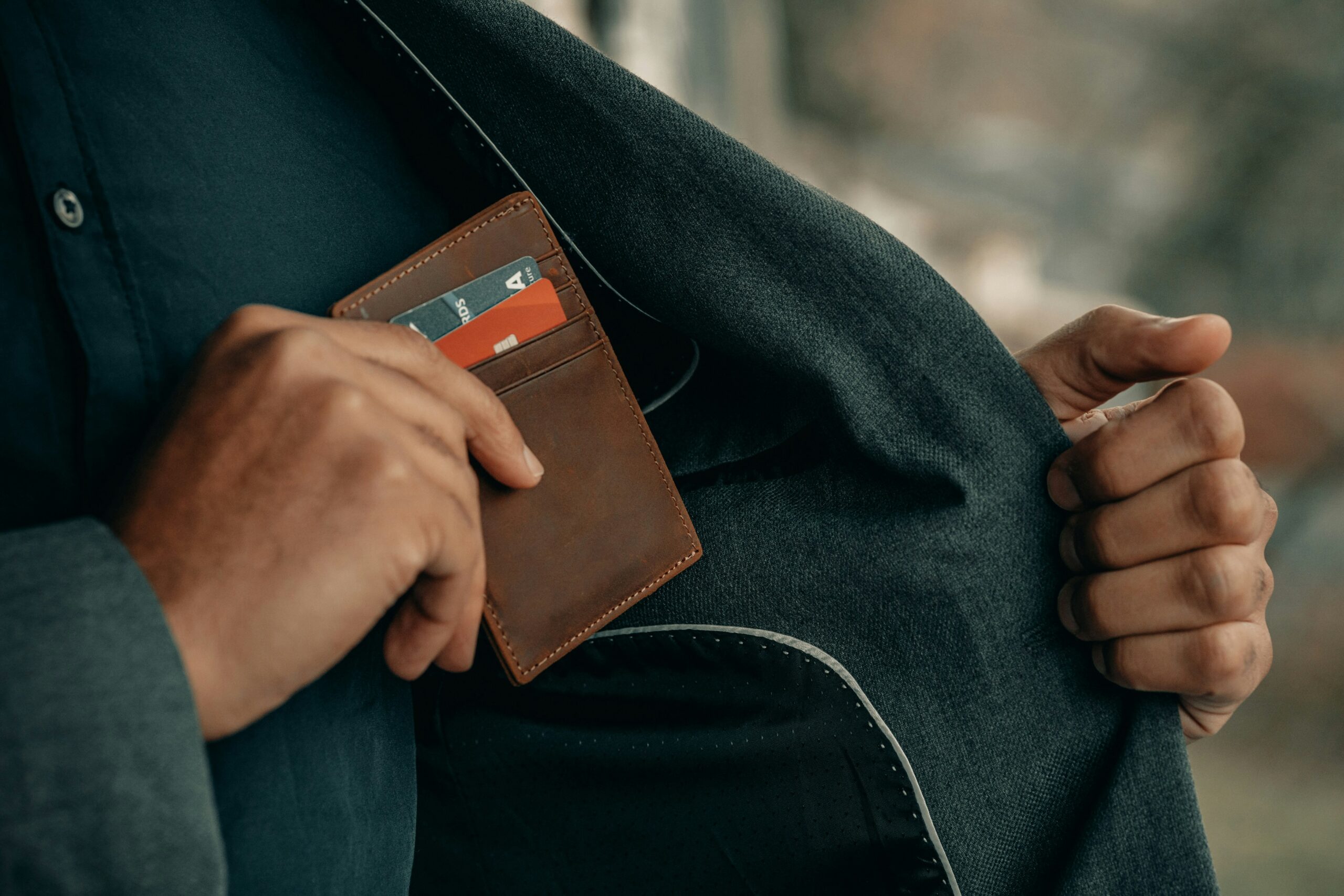 person putting wallet back in coat pocket